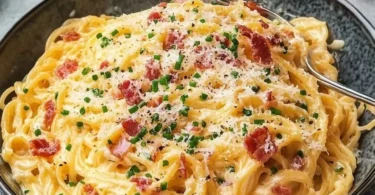 Eier-Nudeln mit Speck und Parmesan auf einem Teller serviert.