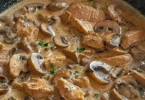 Kalbfleisch mit Champignons auf einem Teller serviert, dekoriert mit frischen Kräutern.