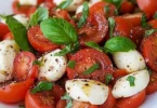 Tomatensalat mit Mozzarella und Basilikum auf einem weißen Teller