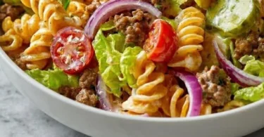 Big Mac Pasta-Salat in einer Schüssel, dekoriert mit frischen Kräutern.
