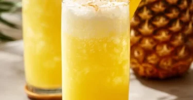 Erfrischende Ananaslimonade in einem Glas mit Ananasstücken