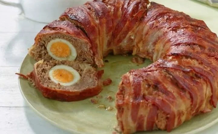 Hackbraten mit Überraschung serviert auf einem rustikalen Holzbrett.
