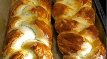 Frischer Hefezopf mit goldbrauner Kruste auf einem Holzbrett.