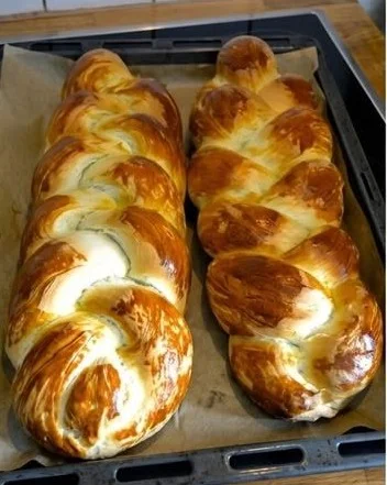 Frischer Hefezopf mit goldbrauner Kruste auf einem Holzbrett.