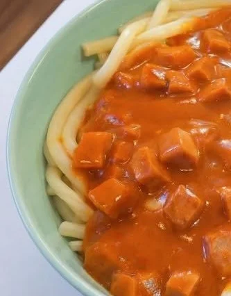 Makkaroni mit Tomatensoße und Jagdwurst auf einem Teller serviert
