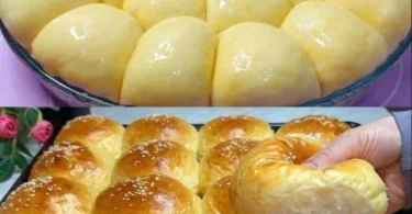 Leckere frisch gebackene Milchbrötchen auf einem Holzbrett angerichtet