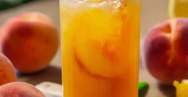 Selbstgemachte Pfirsich-Limonade in einem Glas mit frischen Pfirsichen