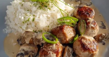 Reis-Pfanne mit Pilzen und grober Bratwurst auf einem Teller serviert