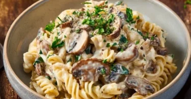 Schnelle Bärlauch-Pasta mit Feta und Champignons auf einem Teller serviert.
