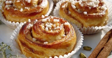 Schwedische Hefebun mit Zimt und Zucker, frisch gebacken auf einem Holztisch.