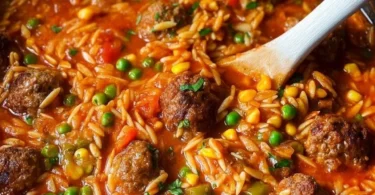 Bunte Orzo-Pfanne mit Hackbällchen und Gemüse auf einem Teller serviert.