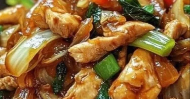 Chinesische Hahnchenpfanne mit Spitzkohl und Zwiebeln auf einem Teller serviert.