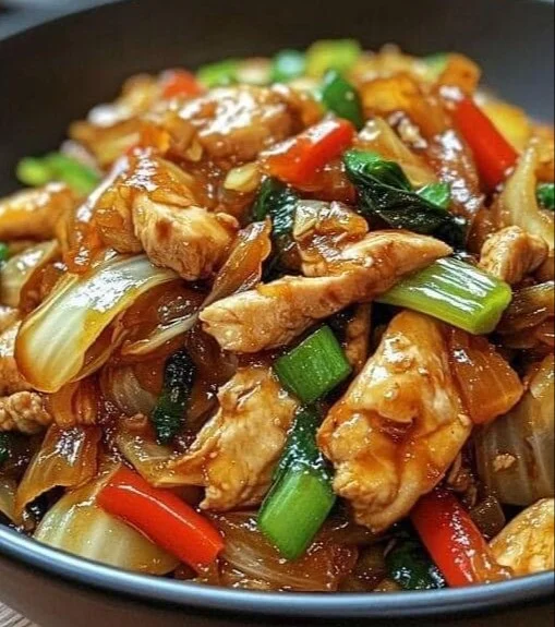 Chinesische Hahnchenpfanne mit Spitzkohl und Zwiebeln auf einem Teller serviert.
