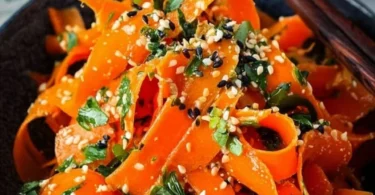 Karottensalat mit Ingwer-Sesam-Dressing auf einem Teller serviert.