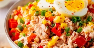 Leckerer Thunfisch-Salat mit Eiern, Mais und Paprika auf einem Teller serviert.
