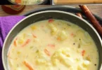 Ultracremige Blumenkohlsuppe in einer Schüssel, garniert mit frischen Kräutern