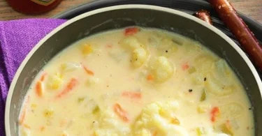 Ultracremige Blumenkohlsuppe in einer Schüssel, garniert mit frischen Kräutern