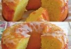 Zitronen Joghurtkuchen auf einem Teller, dekoriert mit Zitronenscheiben und Minze