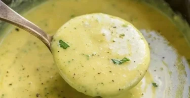 Eine cremige Zucchinisuppe serviert in einer Schüssel mit frischen Kräutern.
