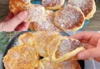 Ein Teller mit frisch gebackenen Apfelpfannkuchen, garniert mit Zimt und Puderzucker.
