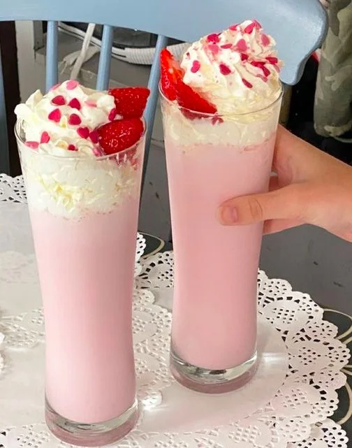 Frischer Erdbeer-Milchshake in einem Glas mit Erdbeeren und Sahne verziert