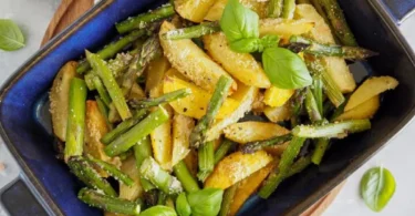 Grüner Spargel aus dem Ofen mit Parmesan-Kartoffeln auf einem Teller.