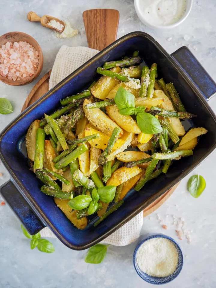 Grüner Spargel aus dem Ofen mit Parmesan-Kartoffeln auf einem Teller.