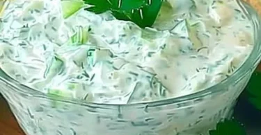 Schüssel mit erfrischendem Gurken-Joghurt-Salat und frischen Kräutern