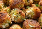 Knusprige Zucchini-Feta-Bällchen frisch aus dem Ofen auf einem Teller serviert.