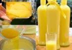 Flasche Limoncello Likor mit frischen Zitronen auf einem Tisch
