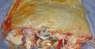 Puffpastry gefüllt mit Salami und Käse auf einem Holzbrett