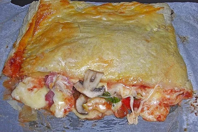 Puffpastry gefüllt mit Salami und Käse auf einem Holzbrett