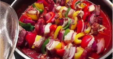 Schaschlik-Spieße in einer leckeren Tomatensauce serviert auf einem Teller.