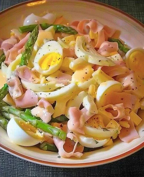 Spargelsalat mit Schinken und Eiern auf einem Teller angerichtet