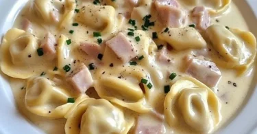 Tortellini in Schinken-Käse-Sahne-Sauce auf einem Teller serviert
