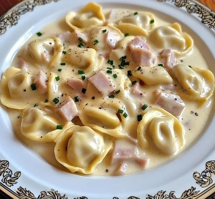 Tortellini in Schinken-Käse-Sahne-Sauce auf einem Teller serviert