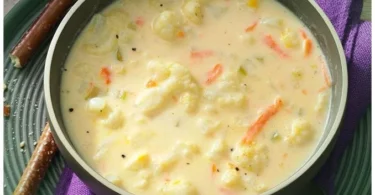 Ultracreamige Blumenkohlsuppe in einer Schüssel mit frischen Kräutern garniert.