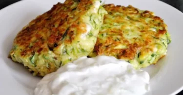 Zucchini-Feta-Patties mit Tzatziki auf einem Teller