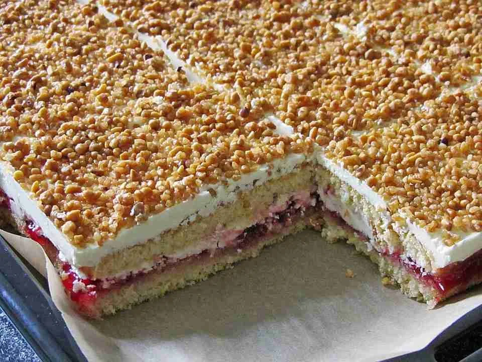 Frankfurter Kranz Schnitten auf einem Teller, dekoriert mit Kirschen und Sahne.