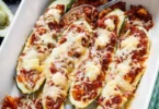 Leckere gefüllte Zucchini mit Gemüse und Käse auf einem Teller.