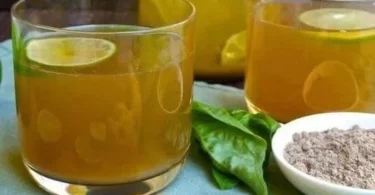 Ein Glas Ingwer Zitronenwasser mit frischen Zutaten auf einem Tisch.