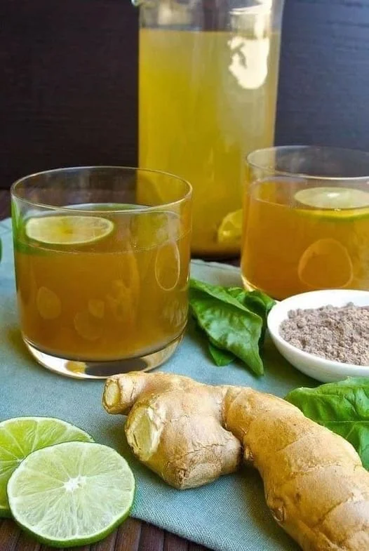 Ein Glas Ingwer Zitronenwasser mit frischen Zutaten auf einem Tisch.