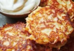 Zwei goldbraune Kartoffelpuffer auf einem Teller, serviert mit Apfelmus