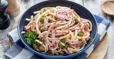 Leckerer Wurst- und Käse-Salat auf einem Teller, dekoriert mit frischen Kräutern.