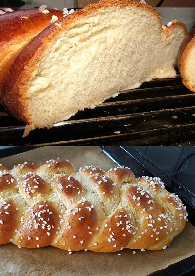 Frisch gebackenes Zopfbrot auf einem Holzbrett, dekoriert mit Sesam.