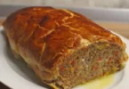 Käse-Fleischlaib in Blätterteig serviert auf einem Holzbrett