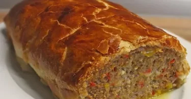 Käse-Fleischlaib in Blätterteig serviert auf einem Holzbrett