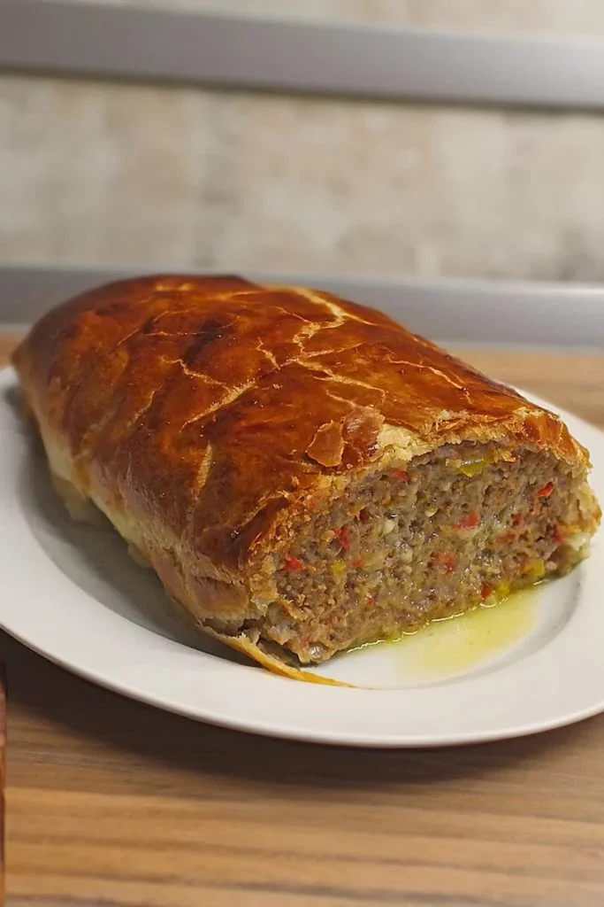 Käse-Fleischlaib in Blätterteig serviert auf einem Holzbrett