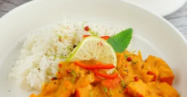 Leckeres Kürbis-Curry mit Kokosnussmilch in einer bunten Schüssel serviert.