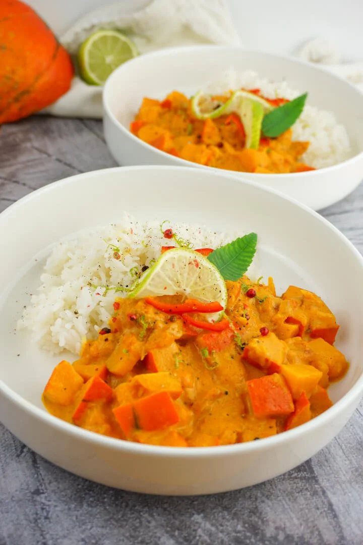 Leckeres Kürbis-Curry mit Kokosnussmilch in einer bunten Schüssel serviert.